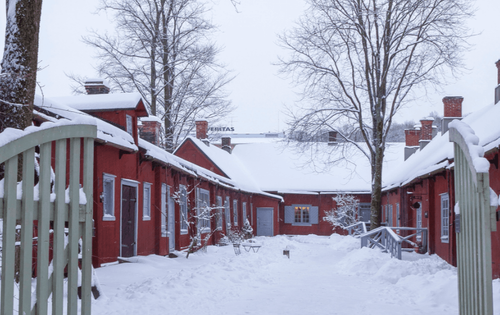 The courtyard of the Pharmacy Museum and the Qwensel House in the winter. Red wooden buildings with white window frames.