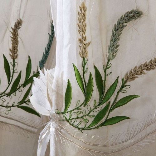 valkoiselle pukukankaalle kirjottuja kasvikuvioita.