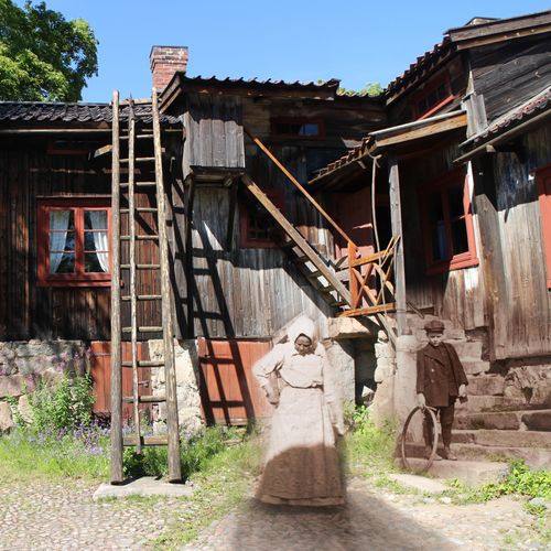 nainen ja nuori poika 1800-luvulta nyky-Luostarinmäellä talon pihalla.